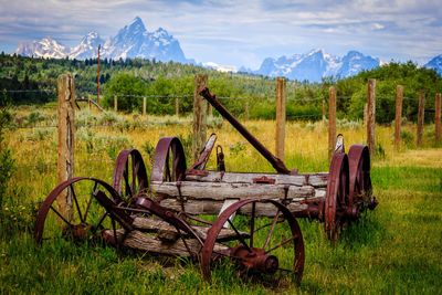 Abandoned cart on field against sky