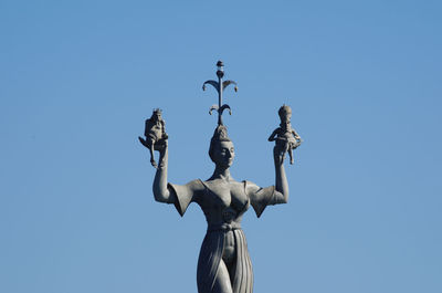 Low angle view of angel sculpture against clear blue sky