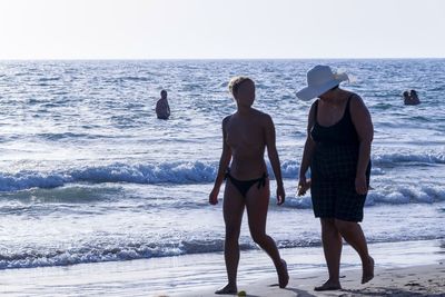 Rear view of men walking on beach