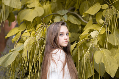 Portrait of woman standing by leaves