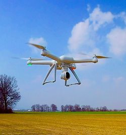 Airplane flying over field against sky