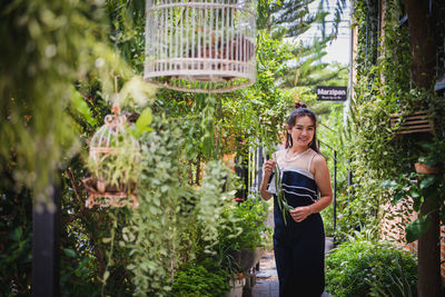 Portrait of a smiling young woman standing against plants