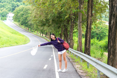 Portrait of happy woman gesturing while standing on road