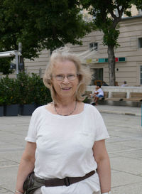 Portrait of smiling mature woman standing on footpath