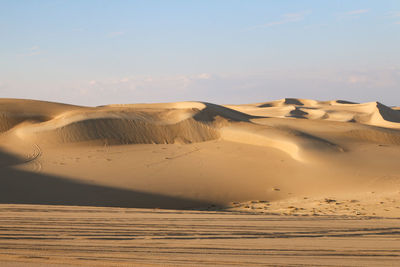 Sand dunes in desert against sky