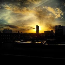 View of city against cloudy sky during sunset