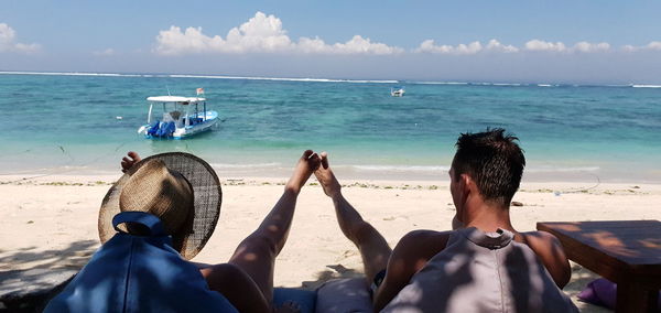 Rear view of women relaxing on beach