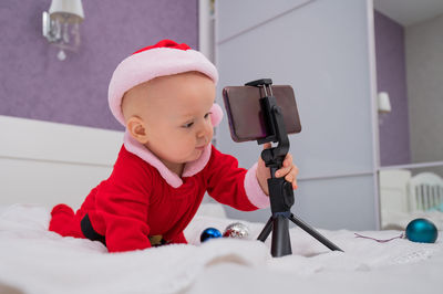 Cute baby boy holding mobile with tripod