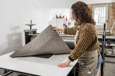 Female artist operating a manual vintage industrial printer.