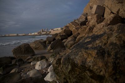 Rock formations at beach against sky