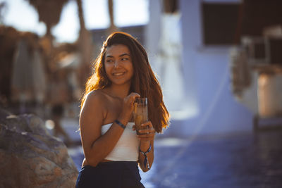 Smiling young woman having drink at beach