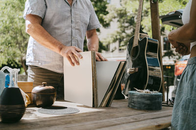 Midsection of male customer buying records at flea market