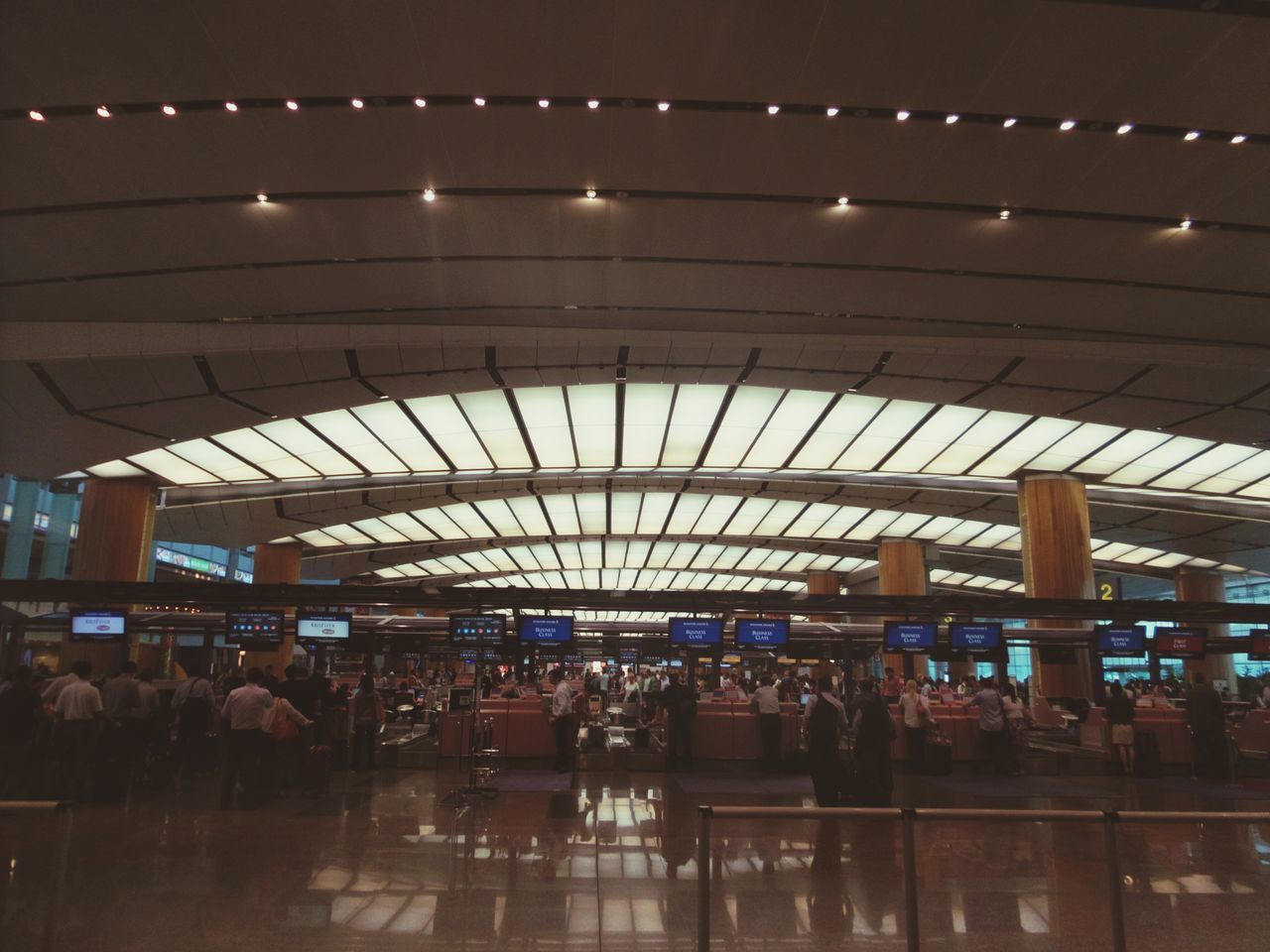 illuminated, indoors, ceiling, lighting equipment, night, large group of people, men, lifestyles, in a row, person, leisure activity, built structure, modern, electric light, airport, light, light - natural phenomenon, repetition, architecture