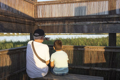 Rear view of grandfather with grandson sitting outdoors