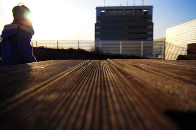 Close-up of wooden table against building during sunset