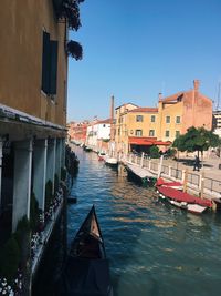 Boats in canal amidst buildings in city against sky