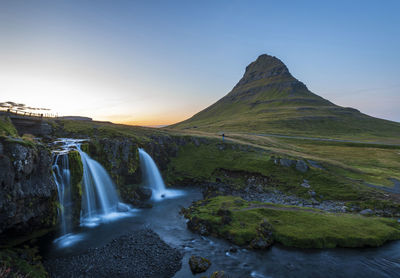 Scenic view of waterfall against sky during sunset