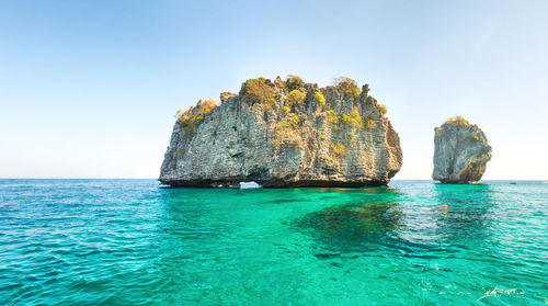 Scenic view of rock formation in sea against clear sky