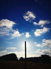 Silhouette fence on field against sky