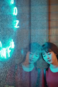 Young woman reflecting on wall with illuminated text