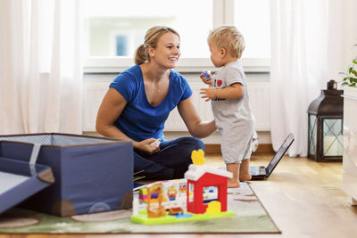 Happy mother playing with baby boy at home