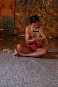 Full length of man sitting on floor