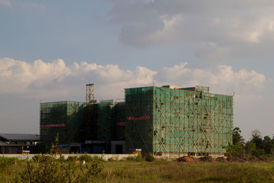 Stack of industry on field against sky