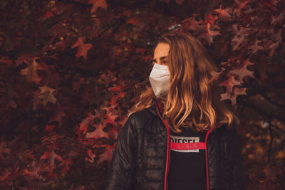 Young woman standing by maple leaves during autumn