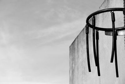 Low angle view of metal hanging on building against sky