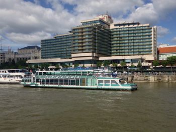 Boats in river by city against sky