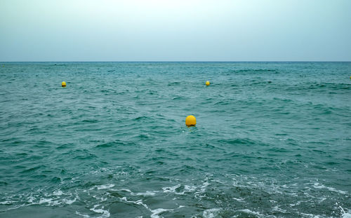 Background of scenic view of sea against clear sky with yellow buoys