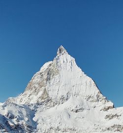 Low angle view of snowcapped mountain against clear sky