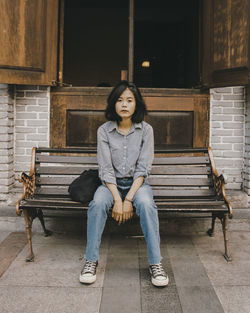 Portrait of woman sitting on bench outdoors