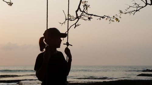 Silhouette man looking at sea against sky during sunset