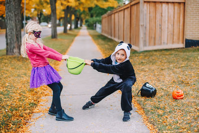 Full length of sibling playing on footpath during winter