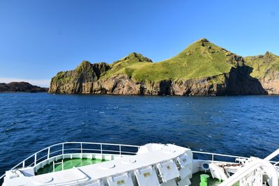 Scenic view of sea and mountains against clear blue sky