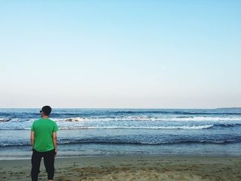 Rear view of man looking at sea against clear sky