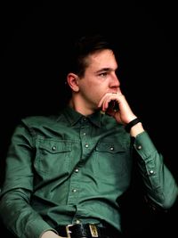 Portrait of young man looking away over black background