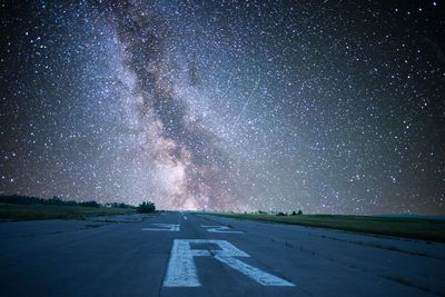 Airport runway against star field sky at night