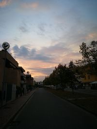 Street amidst buildings against sky during sunset
