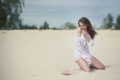 Young woman on sand at beach against sky