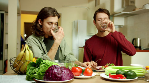 Young couple eating food in kitchen at home