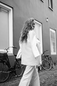 Woman with bicycle standing against wall