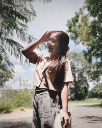 Full length of young woman standing by tree