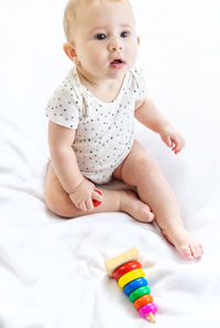 Cute baby girl with toy on bed