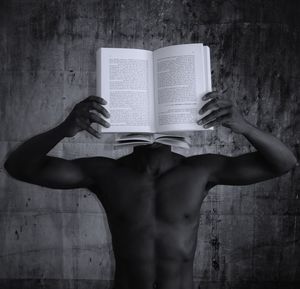 Midsection of woman reading book against wall