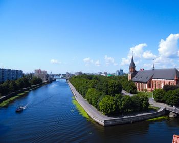 River amidst buildings in city against blue sky