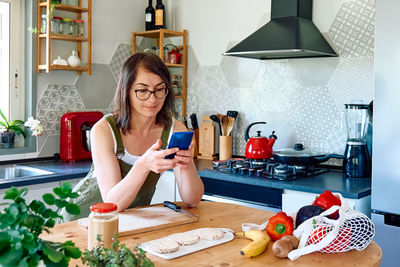 Woman enjoying her healthy breakfast checking on her smart phone at home.