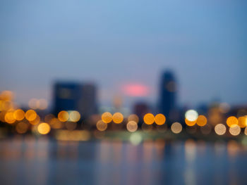 Defocused image of illuminated city against clear sky at night