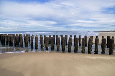 Wooden posts on beach against sky